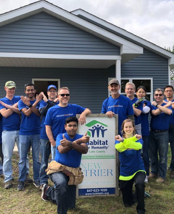Baxter employees pose in front of a Habitat for Humanity Home